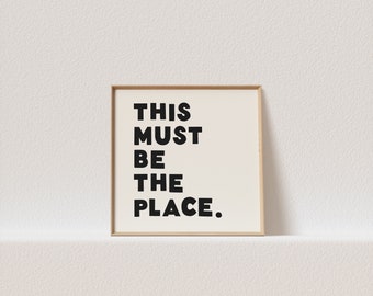 May include: A framed print with the text "THIS MUST BE THE PLACE." in black bold letters on a white background.