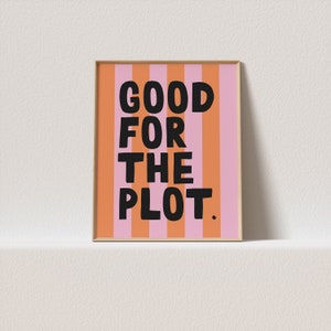 Pode incluir: Impressão artística emoldurada com o texto "GOOD FOR THE PLOT" em letras pretas em negrito. O fundo apresenta listras verticais em tons alternados de laranja e rosa. A obra de arte é exibida em uma moldura marrom clara.