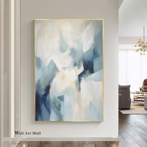 May include: Abstract painting with a gold frame. The painting features a white background with blue and gray geometric shapes.