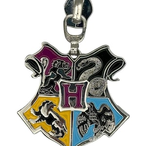 May include: A silver zipper pull charm featuring the Hogwarts house crest. The crest is divided into four sections, each with a different animal and color: a lion on a maroon background, a snake on a black background, a badger on a yellow background, and an eagle on a blue background. The letter "H" is in the center of the crest.