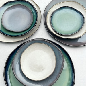 Op de afbeelding: Set van drie keramische borden met een gelaagd ontwerp. De borden zijn in tinten blauw, groen en wit. De borden zijn perfect om hapjes, desserts of hoofdgerechten op te serveren.