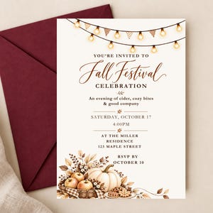 May include: A cream-colored invitation card for a Fall Festival Celebration featuring a string of glowing lights at the top and a basket of pumpkins and apples at the bottom. The text includes event details, date, time, and location, paired with a dark red envelope.