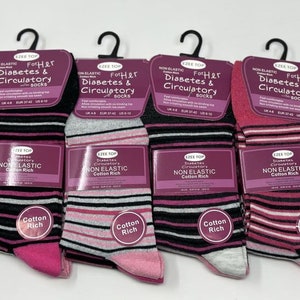 Op de afbeelding: Vier paar gestreepte sokken met roze, zwarte en grijze strepen. De sokken zijn gelabeld met "For Her Diabetes & Circulatory Socks" en "Non Elastic Cotton Rich".