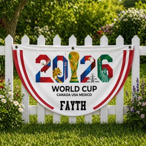 May include: A white banner with red trim is displayed on a white picket fence. The banner features the text "2026 WORLD CUP CANADA USA MEXICO" and the name "FAYTH". The numbers are decorated with images.
