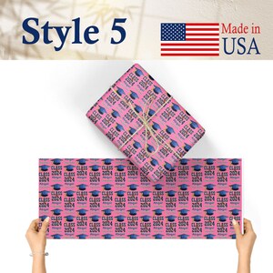 May include: Pink wrapping paper with a repeating pattern of blue graduation caps and the text "Class 2024 Abigail".
