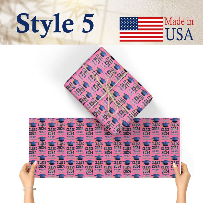 May include: Pink wrapping paper with a repeating pattern of blue graduation caps and the text "Class 2024 Abigail".