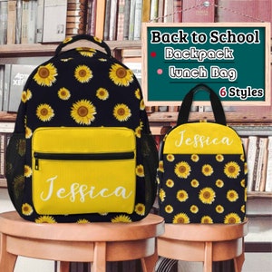 May include: A black and yellow sunflower print backpack and lunch bag set. The backpack has a yellow front pocket with a zipper and a mesh side pocket. The lunch bag has a black handle and a zipper closure. Both items have the name "Jessica" printed on them.  Back to School. Backpack. Lunch Bag. 6 Styles.