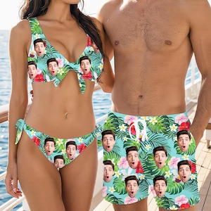 May include: Matching turquoise bikini and swim trunks set. The swimwear features a repeating pattern of a surprised face, tropical flowers, and green leaves. The bikini top has a tie front, and the bottoms have tie sides. The swim trunks have a drawstring waist.