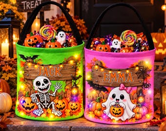 Puede incluir: Dos cubos de Halloween cilíndricos para dulces con asas negras. El cubo izquierdo es verde, con un esqueleto, calabazas y el nombre JACK. El cubo derecho es rosa, con un fantasma, calabazas y el nombre EMMA. Ambos tienen luces LED integradas.