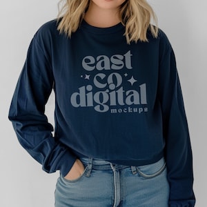May include: A navy blue long-sleeved shirt with the text "east co digital" in a white, retro font. The text is centered on the shirt and is surrounded by small white stars.