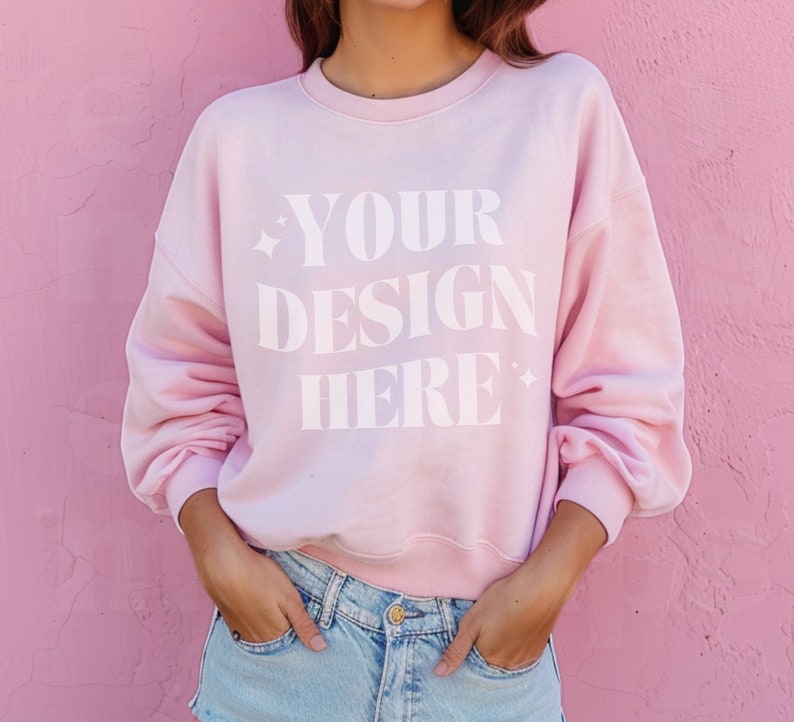 May include: A pink sweatshirt with the text "YOUR DESIGN HERE" printed on the front.