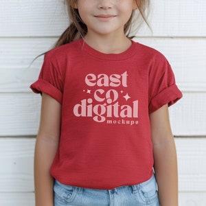 Puede incluir: Una camiseta roja con el texto "east co digital mockups" impreso en rosa en la parte delantera.