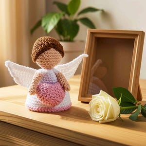 gehäkelte Engelfiguren, die ein rosa Herz  in Händen hält, weißes Kleid mit gehäkelten Flügeln.