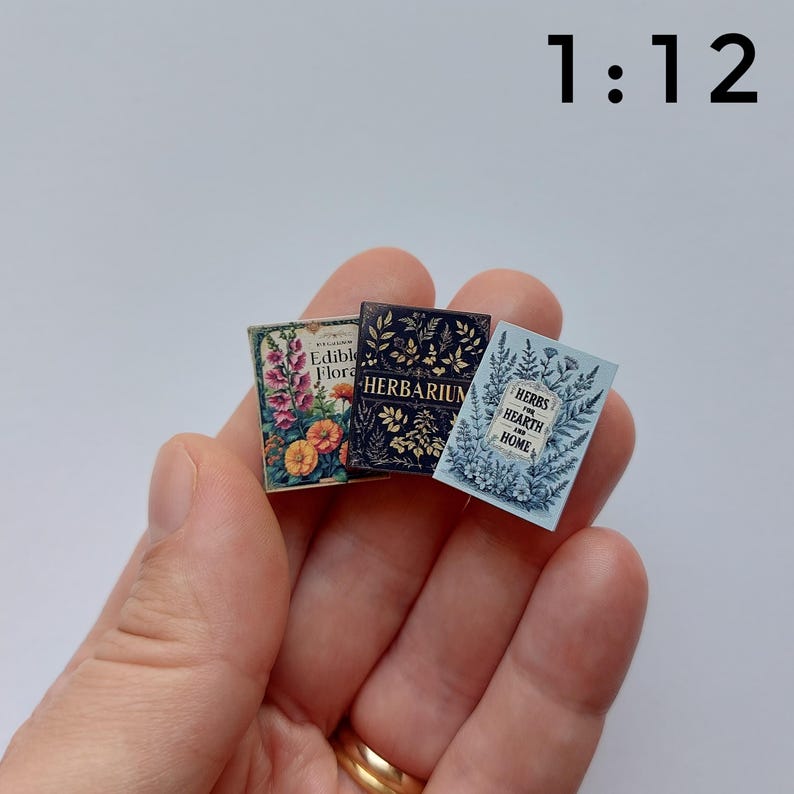 Puede incluir: Tres libros en miniatura con dise&ntilde;os florales. Los libros se titulan "Edible Flora", "Herbarium" y "Herbs for Hearth and Home". Los libros son de varios colores, incluyendo rosa, naranja, azul y azul marino. La escala es 1:12.
