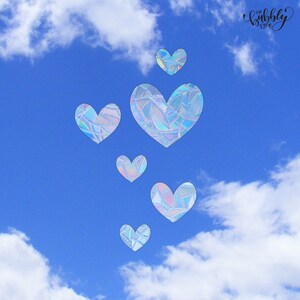 Op de afbeelding: Een helderblauwe lucht met witte wolken en zes iriserende hartvormen. De harten hebben een mozaïekpatroon en variëren in grootte. De tekst "the bubbly type" staat in de rechterbovenhoek.
