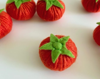 Può includere: Primo piano di diversi pomodori in feltro fatti a mano. I pomodori sono di un rosso vibrante con foglie di feltro verdi. I pomodori in feltro sono disposti su una superficie bianca. Ideali per l'artigianato o come oggetti decorativi.