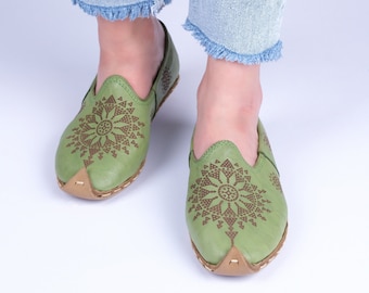 May include: A pair of green leather slip-on shoes with brown embroidered floral designs.