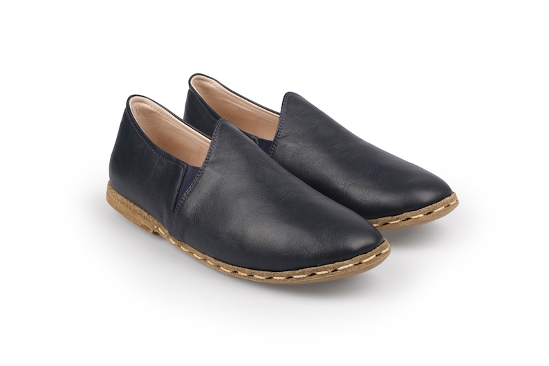 May include: A pair of dark blue leather slip-on shoes with a brown stitched sole.