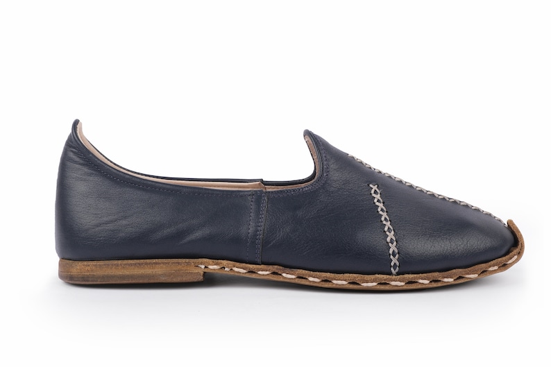 May include: A pair of navy blue leather slip-on shoes with a decorative stitch detail around the edges.