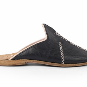 May include: Black leather slip-on shoes with a pointed toe and a decorative stitch detail. The shoes have a brown leather sole.
