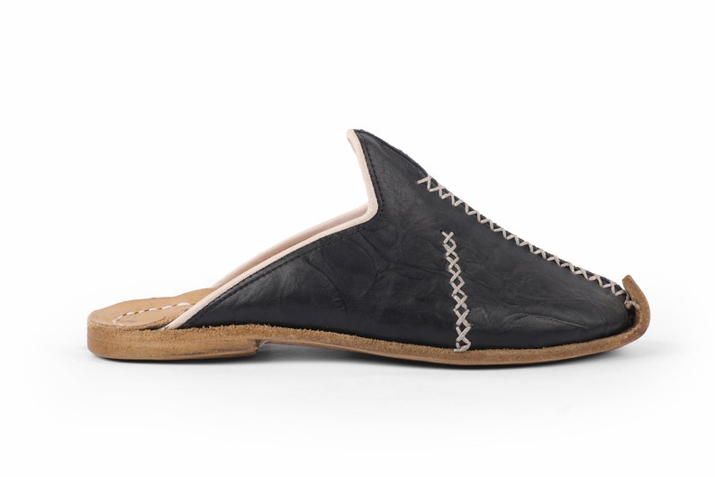 May include: Black leather slip-on shoes with a pointed toe and a decorative stitch detail. The shoes have a brown leather sole.