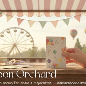 May include: A rectangular notebook featuring a watercolor illustration of colorful balloons in shades of red, yellow, blue, green, and purple against a white background, with thin brown strings extending from each balloon.