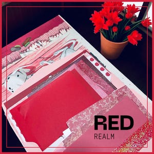 May include: A collection of red and pink paper sheets and patterned scrapbook paper. The text "RED REALM" is visible. A small terracotta pot with red flowers sits in the background. The paper has various textures and patterns.