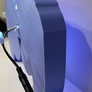 May include: A blue, 3D printed cloud-shaped night light with a white cord and a black power adapter. The light is illuminated with a blue glow.