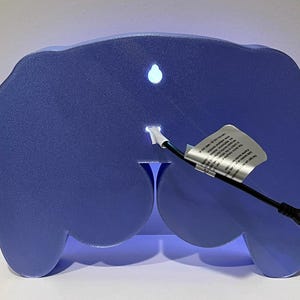May include: A blue light-up controller shaped night light with a white cord and plug.