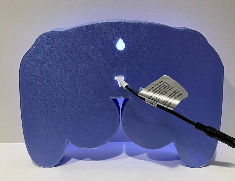 May include: A blue light-up controller shaped night light with a white cord and plug.
