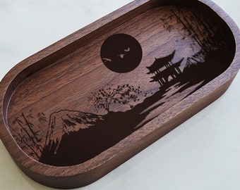May include: A wooden tray with a dark brown finish features a laser-engraved design of a mountain range, a pagoda, a full moon, and trees.