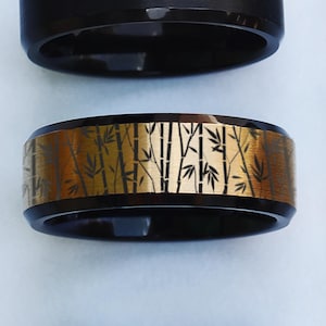 May include: A black and gold ring with a bamboo design. The ring has a brushed finish and a beveled edge.