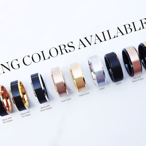 May include: A display of ten different colored rings with black edges. The rings are arranged in a row from left to right. The colors are black with rose gold edges, black with yellow gold edges, black with silver edges, rose gold, yellow gold, silver, black, rose gold with black edges, yellow gold with black edges.