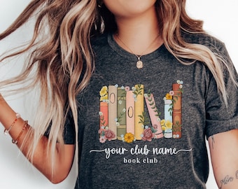 May include: A dark gray t-shirt with a graphic of a stack of colorful books with flowers. The text "your club name book club" is printed below the graphic.