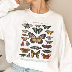 May include: White sweatshirt with a graphic print of a vintage butterfly illustration. The print features a variety of colorful butterflies with the word "Butterflies" at the top.