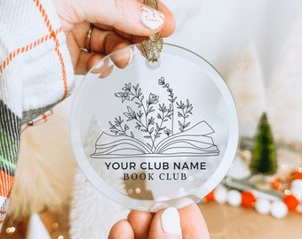 May include: Clear, round ornament with a gold ribbon. The ornament features a black line drawing of an open book with floral elements and the text "YOUR CLUB NAME BOOK CLUB".
