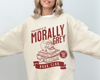 May include: A beige sweatshirt with a red graphic print that says "Proud Member of the Morally Grey Book Club". The graphic features a skull on top of a stack of books and a small red circle that says "Enemies to Lovers Month".