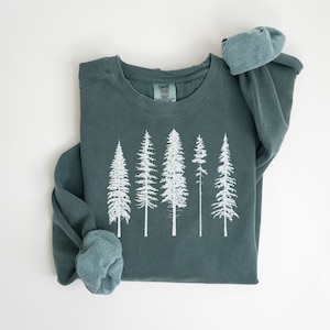 Könnte beinhalten: Ein blaugrüner Pullover mit einer weißen Grafik von fünf Kiefern. Der Pullover hat einen Rundhalsausschnitt und lange Ärmel.