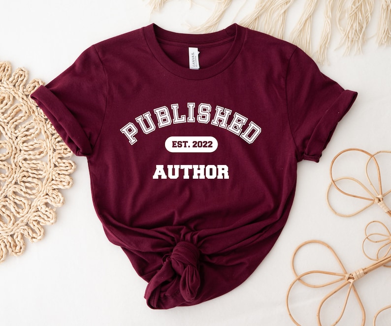 May include: Burgundy t-shirt with white text that reads "Published Est. 2022 Author".