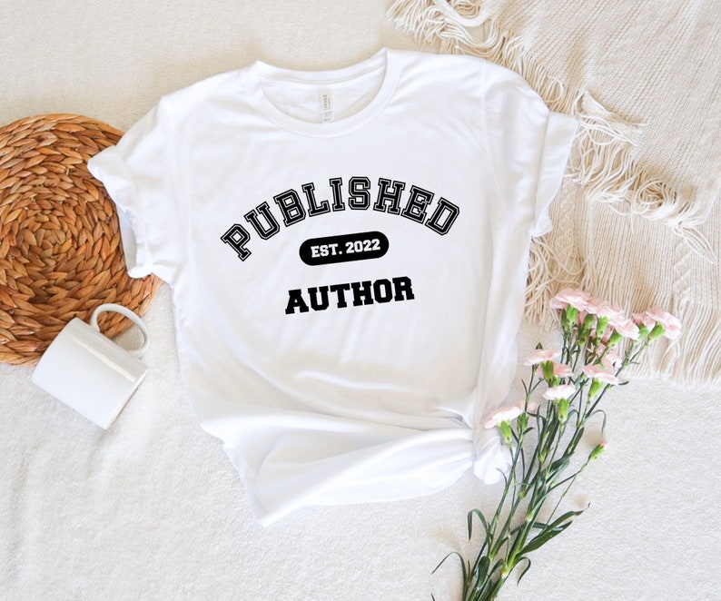 May include: White t-shirt with black text that reads "PUBLISHED EST. 2022 AUTHOR" in a collegiate font.