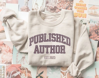 Peut inclure: Un sweat-shirt beige avec le texte "PUBLISHED AUTHOR EST. 2023" en violet.