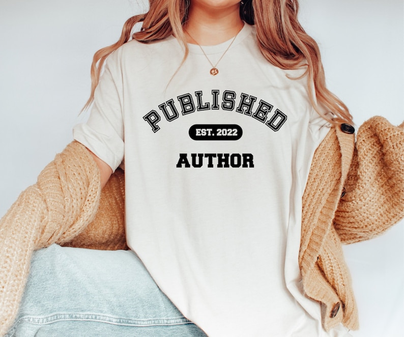 May include: White t-shirt with black text that reads "PUBLISHED EST. 2022 AUTHOR" in a collegiate-style font.