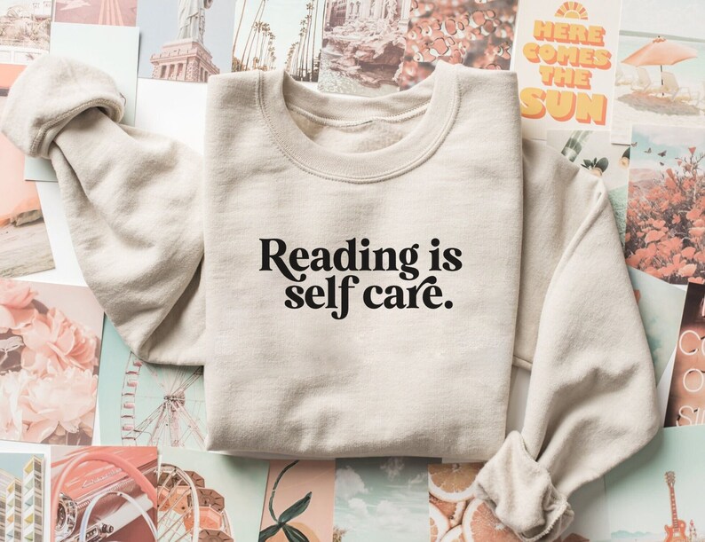 May include: A beige sweatshirt with the text "Reading is self care." printed in black.