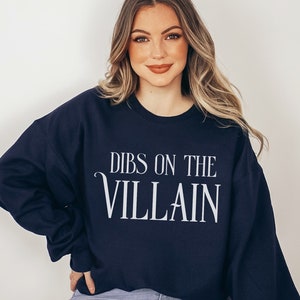 K&ouml;nnte beinhalten: Marineblaues Sweatshirt mit dem wei&szlig;en Text "DIBS ON THE VILLAIN". Das Sweatshirt mit Rundhalsausschnitt ist einfarbig. Das Wort "NAVY" ist unten links aufgedruckt.