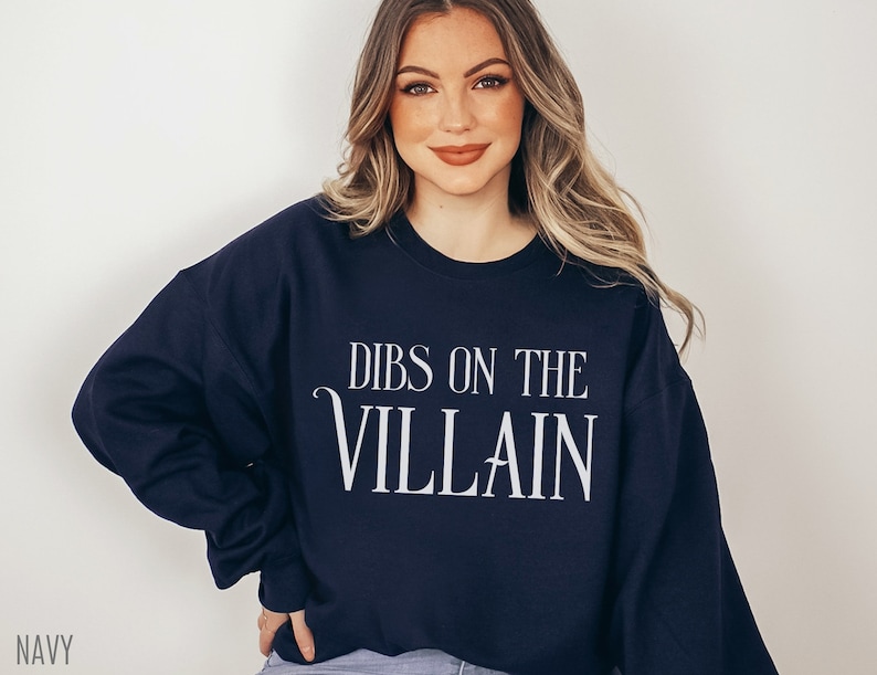 K&ouml;nnte beinhalten: Marineblaues Sweatshirt mit dem wei&szlig;en Text "DIBS ON THE VILLAIN". Das Sweatshirt mit Rundhalsausschnitt ist einfarbig. Das Wort "NAVY" ist unten links aufgedruckt.