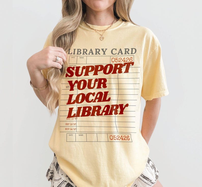 Woman wearing oversized yellow butter t shirt with retro library card design and bold support your local library lettering