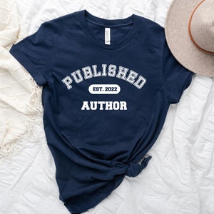May include: Navy blue t-shirt with white text that reads "PUBLISHED EST. 2022 AUTHOR".