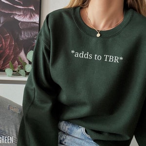 May include: Forest green sweatshirt with the text "*adds to TBR*" in white.