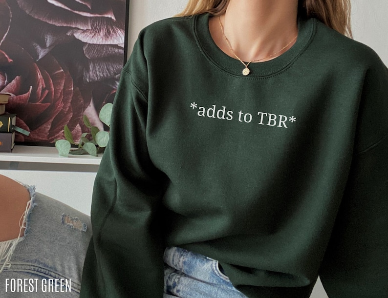 May include: Forest green sweatshirt with the text "*adds to TBR*" in white.