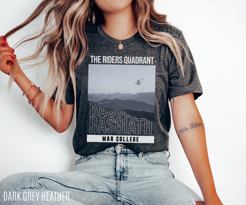 K&ouml;nnte beinhalten: Ein dunkelgraues T-Shirt mit einem Grafikdruck eines Gebirges und dem Text "The Riders Quadrant, Basquiat, War College".